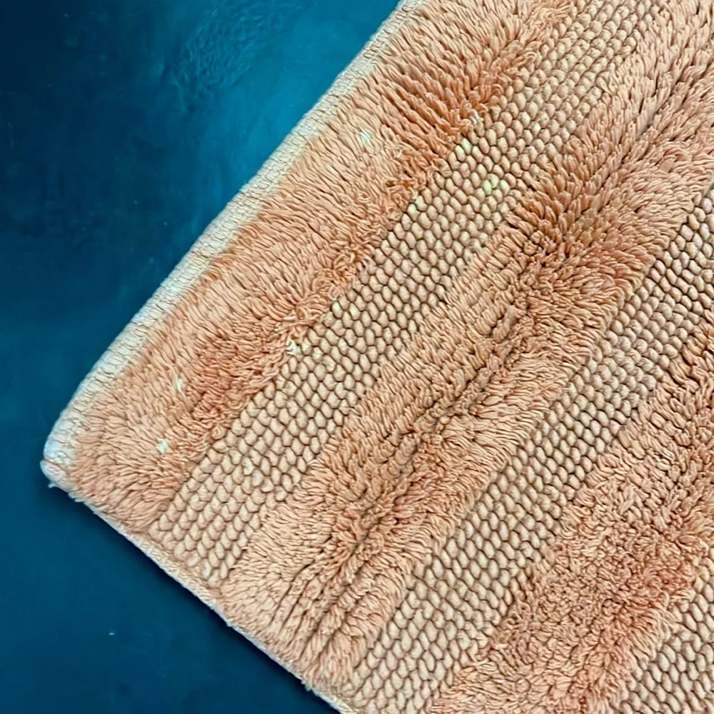 Set of two Lacoste bathroom mats in orange.
